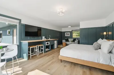 a bedroom with blue walls and a bed and a kitchen at Lakelyn Lodge in Lakeville
