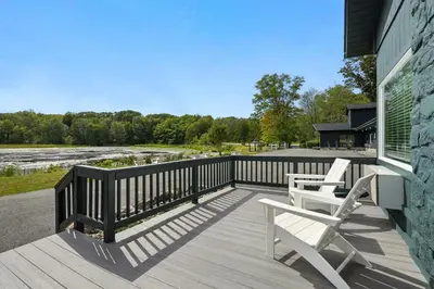 a deck with two white chairs on a house at Lakelyn Lodge in Lakeville