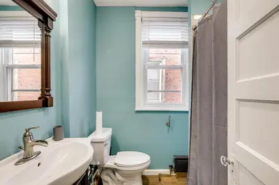 a bathroom with a toilet and a sink and a window at Private Backyard Jawn! Multi-Level Philly Rowhouse in Philadelphia