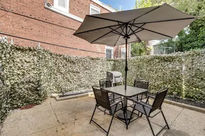 a table and chairs with an umbrella on a patio at Private Backyard Jawn! Multi-Level Philly Rowhouse in Philadelphia