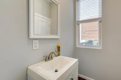 a white bathroom with a sink and a mirror at Private Backyard Jawn! Multi-Level Philly Rowhouse in Philadelphia