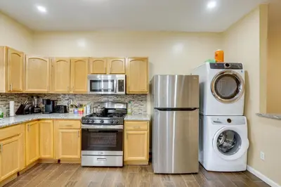 a kitchen with wooden cabinets and stainless steel appliances at Private Backyard Jawn! Multi-Level Philly Rowhouse in Philadelphia