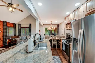 a kitchen with a stainless steel refrigerator next to a living room at Amazing Condo with hot tub and screened in porch 8 passes to lake and beach in Stoddartsville
