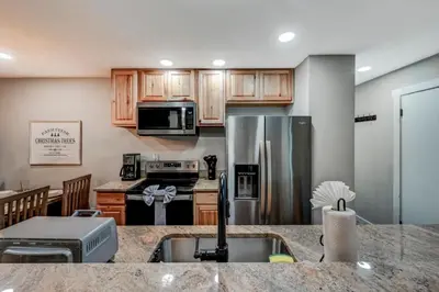 a kitchen with wooden cabinets and a stainless steel refrigerator at Amazing Condo with hot tub and screened in porch 8 passes to lake and beach in Stoddartsville