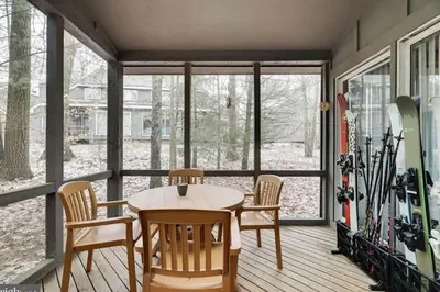 a porch with a table and chairs and snowboards at Amazing Condo with hot tub and screened in porch 8 passes to lake and beach in Stoddartsville