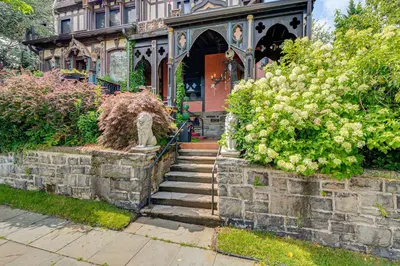 a house with a stone wall and stairs in front at A Retreat in an Historic Estate with Modern Comforts in Scranton