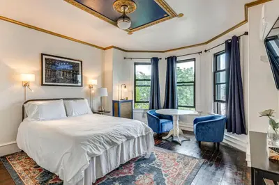 a bedroom with a bed and a desk and windows at A Retreat in an Historic Estate with Modern Comforts in Scranton