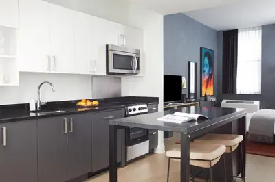 a kitchen with a black table and a microwave at Mint House 70 Pine by Kasa in New York