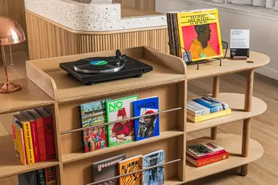 a book shelf with a record player and books at Mint House 70 Pine by Kasa in New York