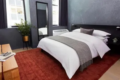 a bedroom with a large white bed with a red rug at Mint House 70 Pine by Kasa in New York