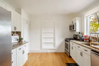 a kitchen with white cabinets and a wooden floor at Elegant Spacious Retreat Perfect For Families in Wilmington