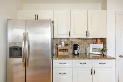 a kitchen with white cabinets and a stainless steel refrigerator at Elegant Spacious Retreat Perfect For Families in Wilmington