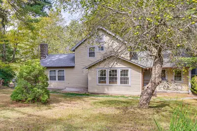 a white house with a tree in the yard at Ski, Swim, Relax Old-Fashioned Poconos Getaway in Pocono Pines