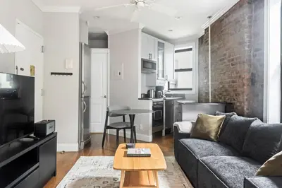 a living room with a couch and a brick wall at Blueground Nolita private entrance nr Bowery NYC-2054 in New York