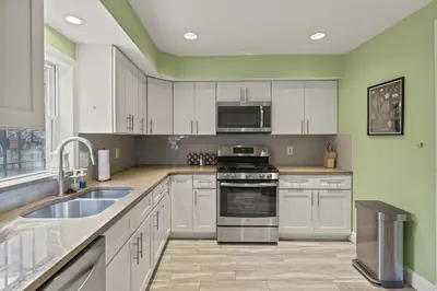 a kitchen with white cabinets and stainless steel appliances at The Bella Vista Townhouse in Philadelphia