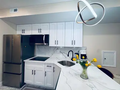 a kitchen with white cabinets and a vase of flowers on a counter at Renovated Modern Apt next to ChinatownConvention in Philadelphia