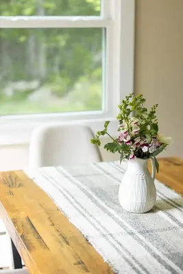 a white vase with flowers sitting on a table at Cozy Cottage in Glen Spey in Glen Spey