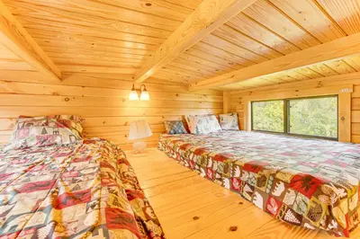 a bedroom with two beds in a log cabin at 5 Mi to Susquehanna Boating! Secluded Log Cabin