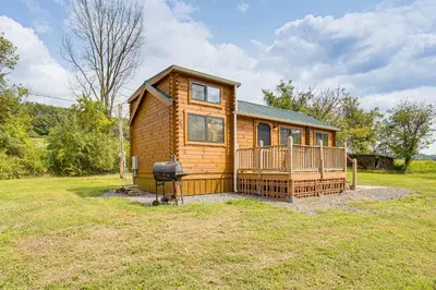 a log cabin with a large porch and a grill at 5 Mi to Susquehanna Boating! Secluded Log Cabin