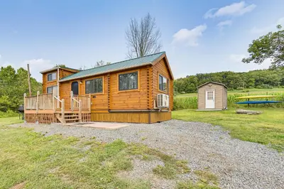 a log cabin with a porch and a house at 5 Mi to Susquehanna Boating! Secluded Log Cabin
