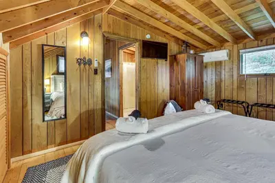 a large bed in a room with wooden walls at Less Than 1 Mi to Lake Cabin with Hot Tub in Greentown! in Greentown