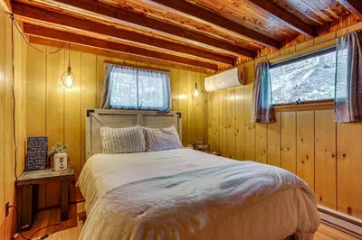 a bedroom with a bed in a log cabin at Less Than 1 Mi to Lake Cabin with Hot Tub in Greentown! in Greentown