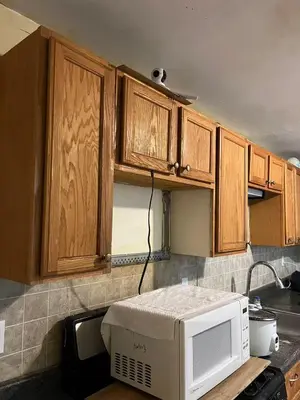a kitchen with wooden cabinets and a microwave on a counter at 2131 queen room With shared Bathroom in Philadelphia