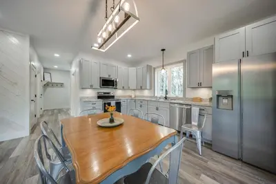 a kitchen with a wooden table and a refrigerator at Waterfront Home with Kayaks, Trails and Petting Zoo!