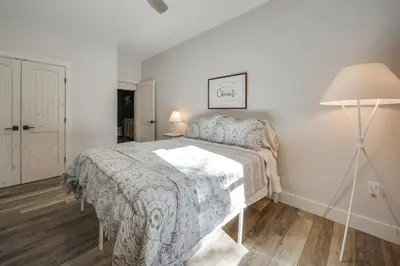 a white bedroom with a bed and a lamp at Waterfront Home with Kayaks, Trails and Petting Zoo!