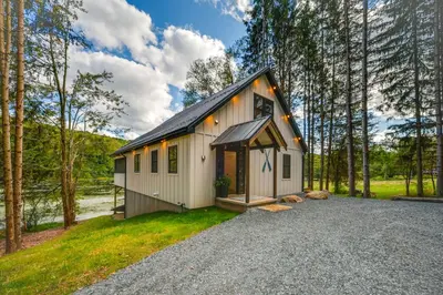a small house in the middle of a forest at Waterfront Home with Kayaks, Trails and Petting Zoo!