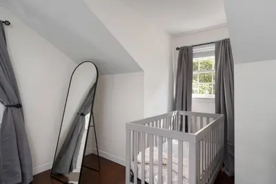 a white nursery with a crib and a mirror at Exclusive Lux Home Near Town • Game Rm • Gym • 4BR in Princeton