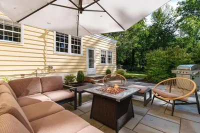 a patio with a couch and a table and an umbrella at Exclusive Lux Home Near Town • Game Rm • Gym • 4BR in Princeton