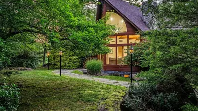 a home in the woods with a large window at Lake Harmony Chalet w Hot Tub Arcades Near Beaches Ski Trails Everpine Lodge by AvantStay in Lake Harmony