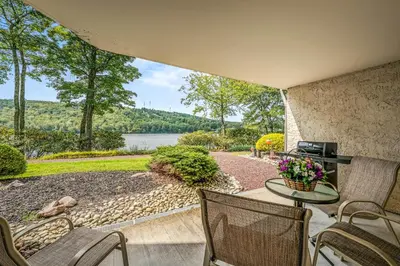 a patio with a table and chairs and a lake at Epic Views and Pool Access! Gem on Big Boulder Lake in Lake Harmony