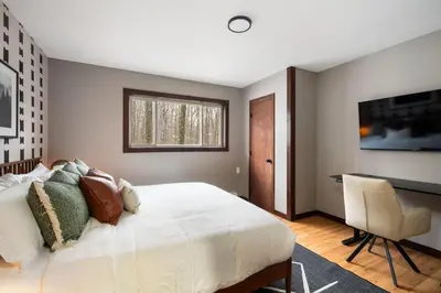 a bedroom with a large white bed and a chair at Cozy Poconos Retreat - pool table, hot tub, fire pit in Tobyhanna