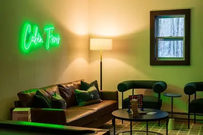 a living room with a couch and a neon sign at Cozy Poconos Retreat - pool table, hot tub, fire pit in Tobyhanna