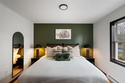 a bedroom with a large white bed with green walls at Cozy Poconos Retreat - pool table, hot tub, fire pit in Tobyhanna