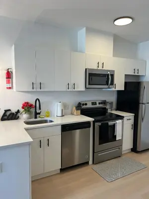 a kitchen with white cabinets and stainless steel appliances at Luxury Queen Studio- Minutes To NYC, EWR & MetLife in Elizabeth