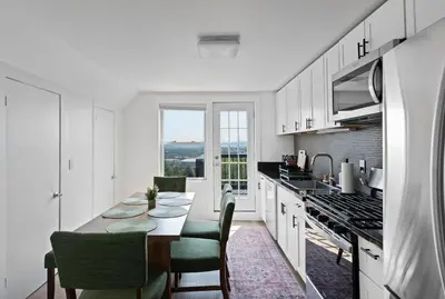 a white kitchen with a table and chairs at Nyc skyline view, 17m- Manhattan, Prime location in Carlstadt