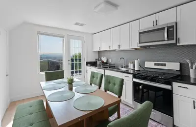 a kitchen with a wooden table and green chairs at Nyc skyline view, 17m- Manhattan, Prime location in Carlstadt