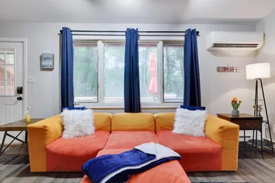 a couch in a living room with blue curtains at Gloria's Hot Tub Game Room Fire Pit in Blakeslee