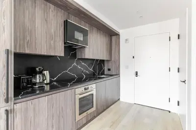 a kitchen with wooden cabinets and a black counter top at Blueground Alphabet City rooftop nr Tompkins Square Park NYC-2057 in New York