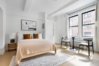 a white bedroom with a bed and a desk at Blueground Lincoln Square view nr Central Park NYC-2065 in New York