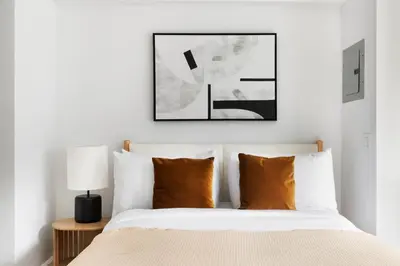 a bedroom with a bed with white sheets and orange pillows at Blueground Lincoln Square view nr Central Park NYC-2065 in New York