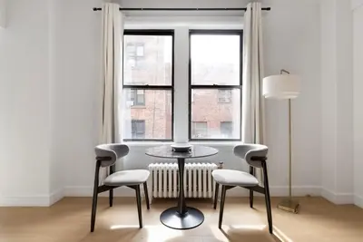 a table and two chairs in a room with a window at Blueground Lincoln Square view nr Central Park NYC-2065 in New York