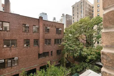 an old brick building with a tree in front of it at Blueground Lincoln Square view nr Central Park NYC-2065 in New York