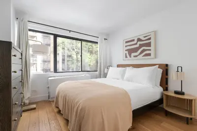 a white bedroom with a large bed and a window at Blueground Midtown East rooftop nr Grand Central NYC-2069 in New York