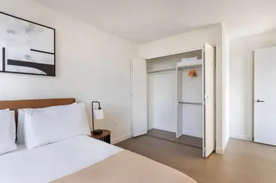 a white bedroom with a bed and a closet at Blueground Hells Kitchen fitness center nr Hudson River Park NYC-2086 in New York