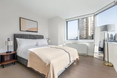a white bedroom with a bed and a large window at Blueground Hells Kitchen fitness center nr Hudson River Park NYC-2086 in New York