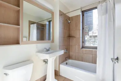 a bathroom with a sink and a bath tub and a mirror at Blueground Hells Kitchen fitness center nr Hudson River Park NYC-2086 in New York